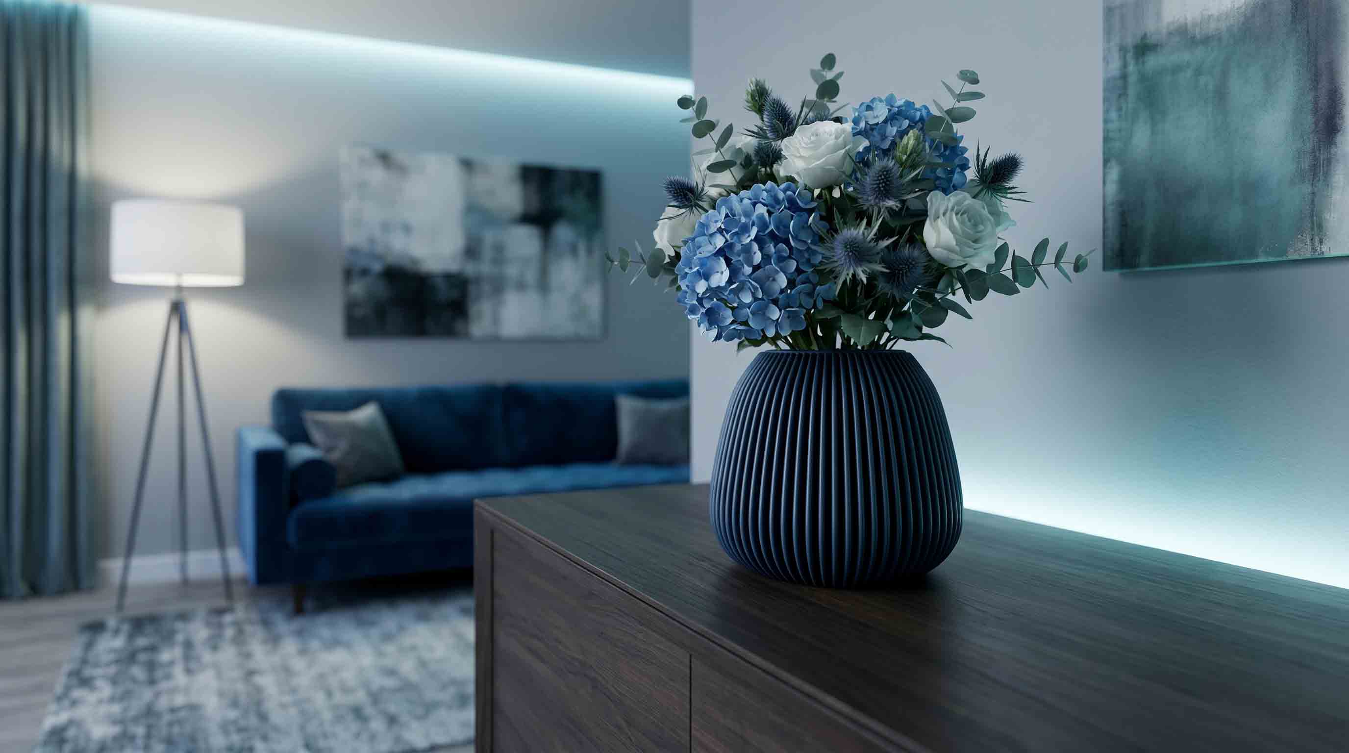 Ein dunkelblau gerippter Keramikvase mit blau-weißen Hortensien und grünen Blättern auf einem Holztisch im Wohnzimmer.