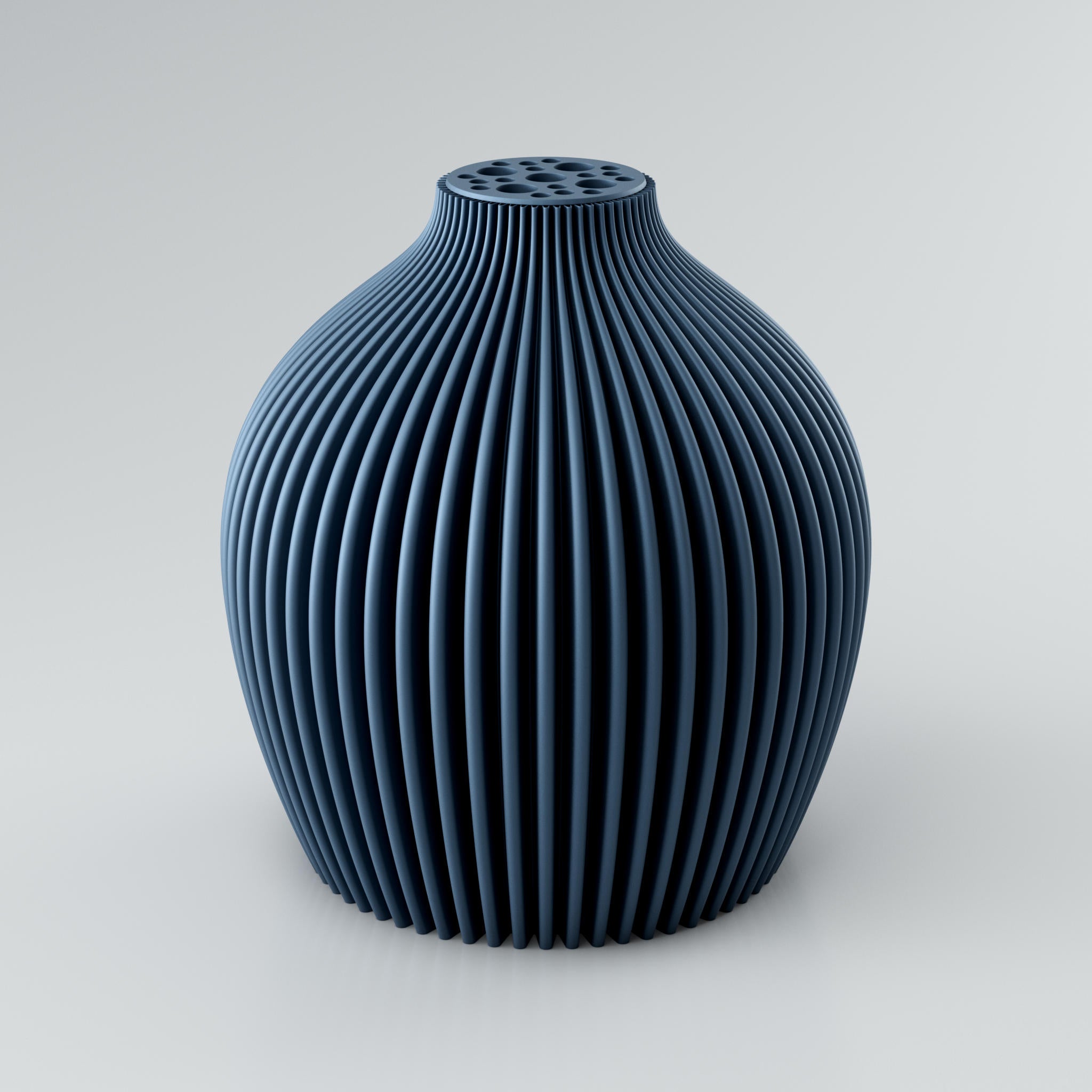 Eine moderne, modulare Designvase namens Voravellie 60 von Blooming3D in einem sanften Beigeton. Die Vase hat eine skulpturale Form mit einer ausgeprägten, präzise ausgearbeiteten Rippstruktur, die für ein faszinierendes Licht- und Schattenspiel sorgt. Am oberen Ende befindet sich ein integrierter Blumenretter mit unterschiedlich großen runden Öffnungen, ideal für stilvolle Trockenblumenarrangements. Die klaren Kanten und die dynamische Form vereinen Architektur und Design in einem Objekt. Die Vase...